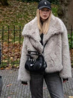 woman in a light grey faux fur jacket and black handbag