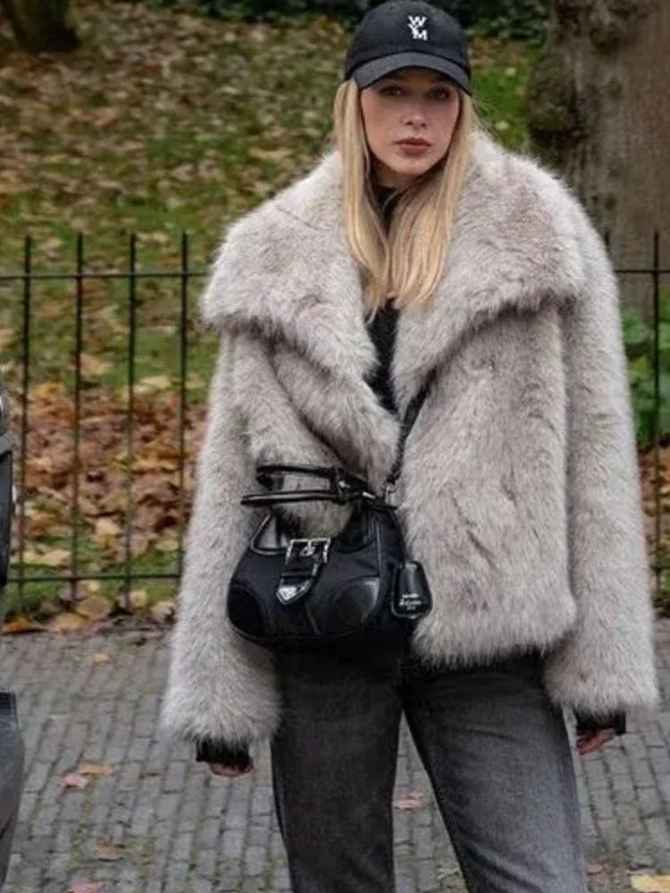 woman in a light grey faux fur jacket and black handbag