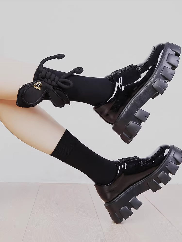 Close-up of black mid-calf socks with a 3D rope bow and gold heart charm.