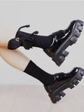 Person wearing black socks with a decorative bow and heart charm with platform shoes.