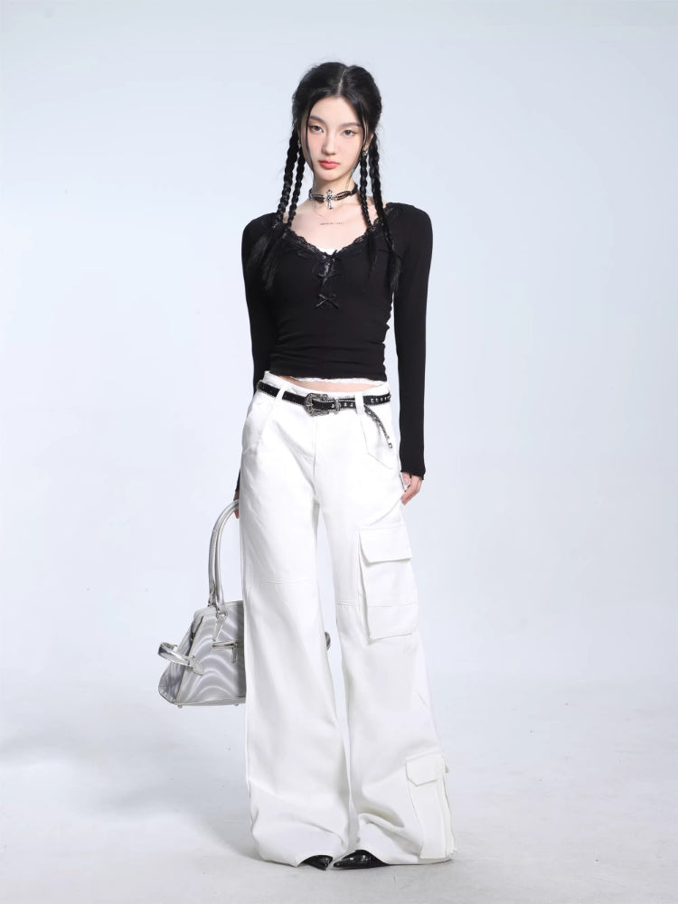 Woman wearing a black long-sleeve ribbed knit top and white cargo pants, accessorized with a belt and holding a silver handbag.