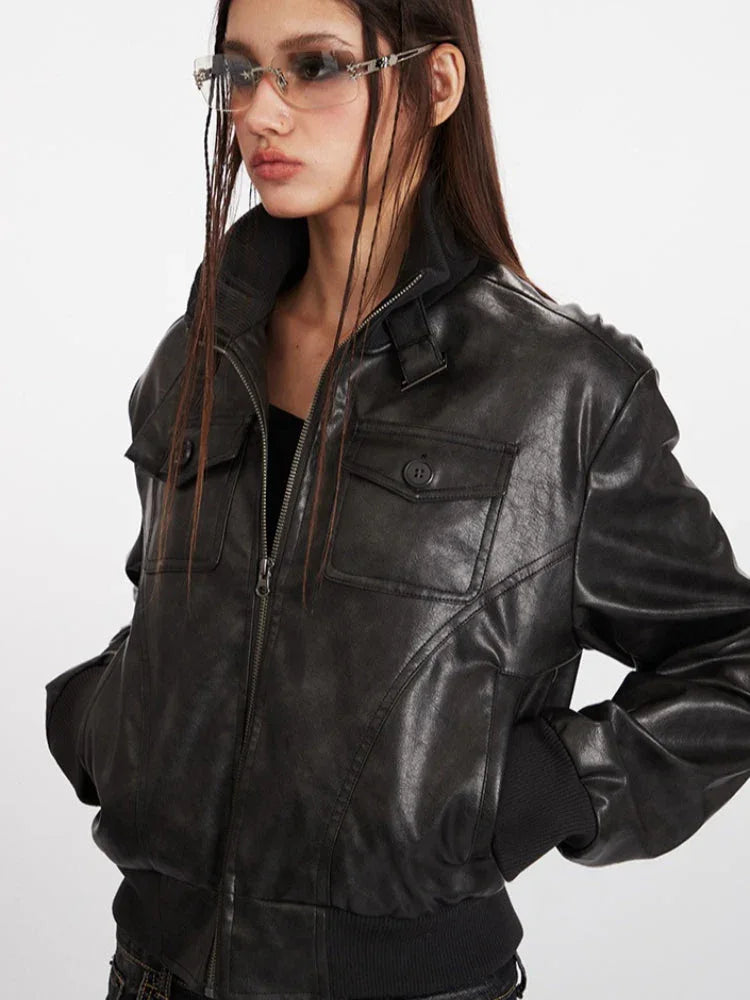 Woman wearing a black faux leather bomber jacket with a stand collar and ribbed cuffs.