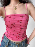 Model wearing a pink cherry print ruched mesh top with adjustable side ties.