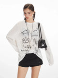 Close-up of a woman wearing a white long-sleeve sheer knit t-shirt with a black dog graphic print and text, and a silver heart pendant necklace.