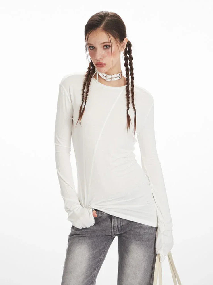 Close-up of a model wearing a white long sleeve top with asymmetrical seam detail.