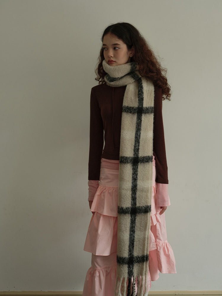 Model posing with a cream and black plaid scarf