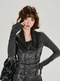 Woman posing with her hand near her face, highlighting the long sleeves with ruched detailing on a dark gray top.