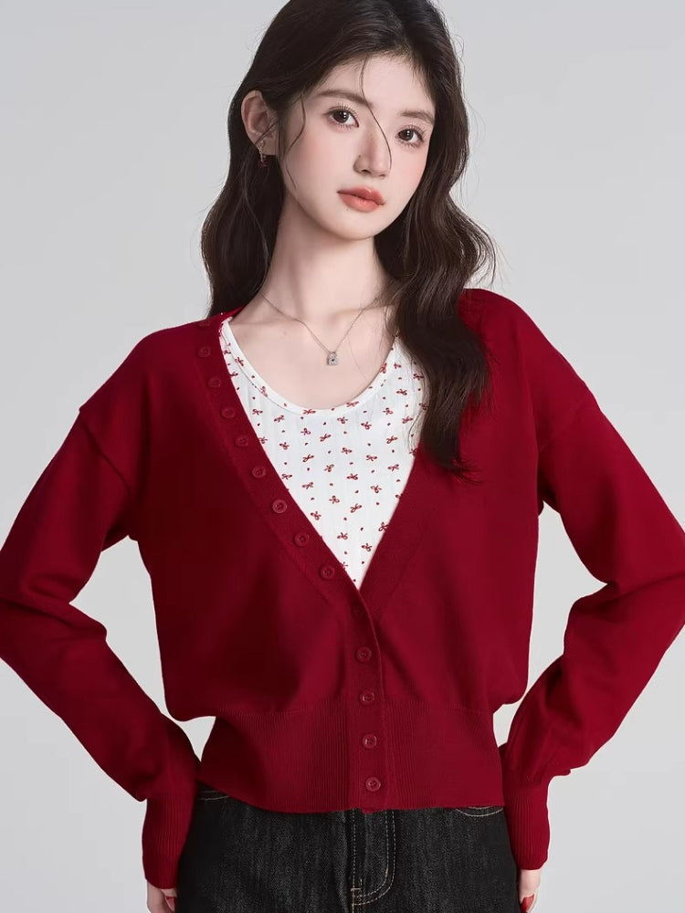 Woman wearing a red knit cardigan over a white floral print camisole Main image