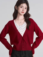 Woman wearing a red knit cardigan over a white floral print camisole