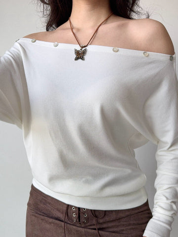 Model wearing a white off-the-shoulder long-sleeve top with button details.