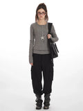 Model wearing a grey faux layered long sleeve henley top with black cargo pants