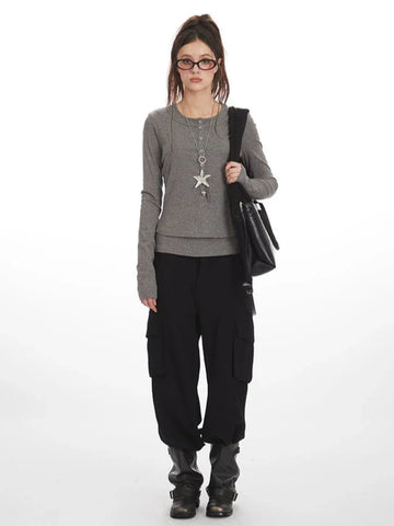 Model wearing a grey faux layered long sleeve henley top with black cargo pants