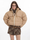 Front view of a woman wearing a beige cropped puffer jacket with a white zipper.