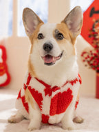 Corgi dog wearing a red and white checkerboard plush dog coat with a festive graphic.