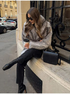Woman smiling while wearing a grey faux fur coat and sunglasses