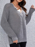 Woman wearing a grey knit V-neck sweater with textured pattern and long sleeves.