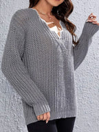 Woman wearing a grey knit V-neck sweater with textured pattern and long sleeves.