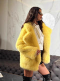 Woman in a yellow faux fur jacket, white blouse, and black shorts