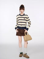 Full-length view of a woman in a striped knit cardigan and brown mini skirt