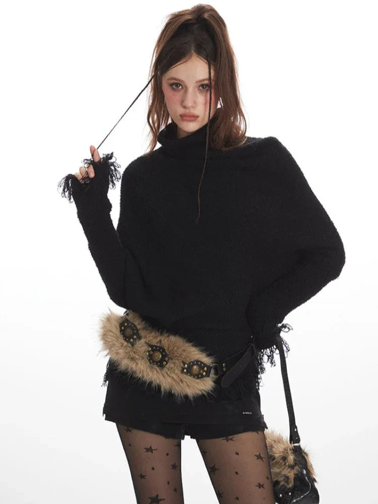 Woman posing with her hand on her head, wearing a black turtleneck sweater with fringed details