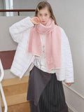 Model posing with a pink knit scarf draped around their neck