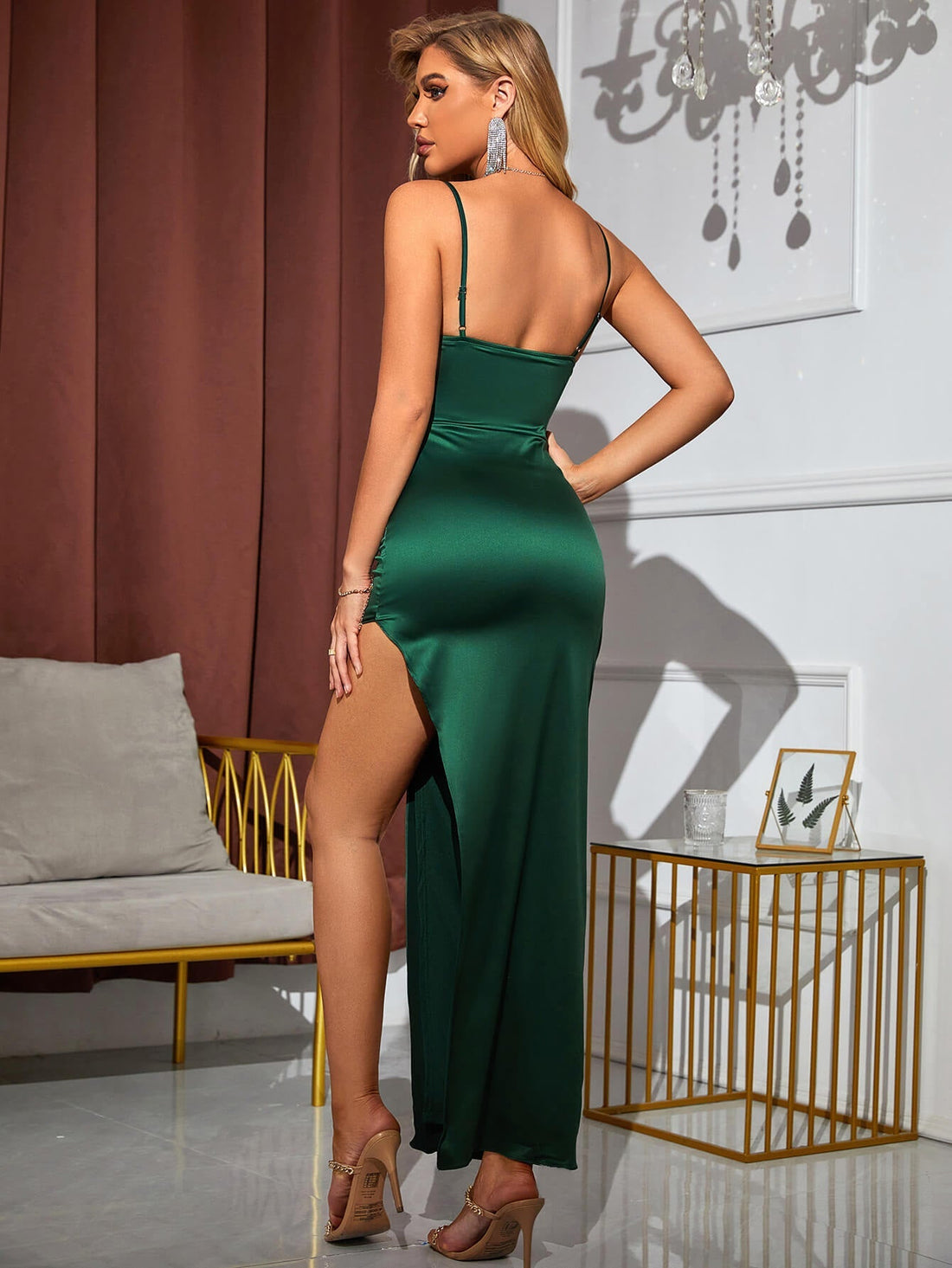 Woman wearing a green satin spaghetti strap formal gown with a high slit