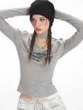 Model posing with hands on head, wearing a grey long-sleeve graphic t-shirt with a choker detail and silver ruffled shorts.