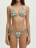 Woman wearing a white and green patterned bikini with halter top and tie-side bottoms