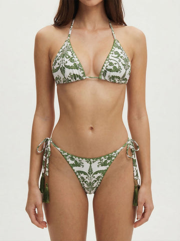Woman wearing a white and green patterned bikini with halter top and tie-side bottoms