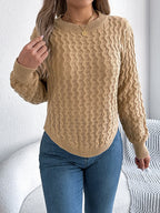 Close-up of a woman's torso showing the detailed knit pattern of a tan sweater.