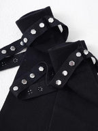 Detail view of the top cuff of black knee-high socks, showing knit texture, stud embellishments, and a strap with hexagonal studs.