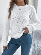 Woman adjusting her sweater, showing the ribbed hem and cuffs of a white knit top