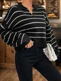 Woman with a white clutch bag wearing a black and white striped cropped knit sweater.