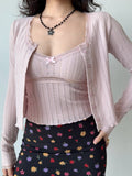 Model showcasing a pink knit cardigan with a cropped silhouette and long sleeves.