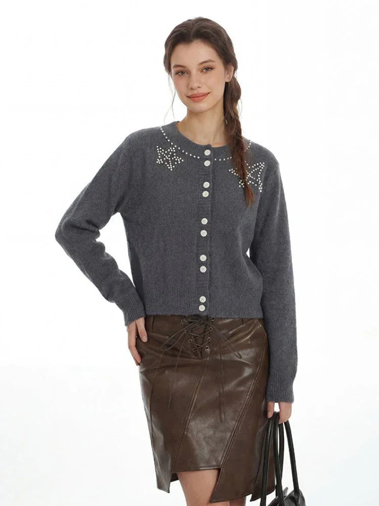 Woman posing in a grey cardigan and brown faux leather skirt, showcasing the outfit.