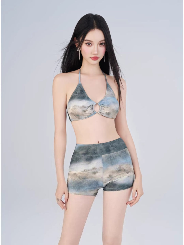 Woman modeling a halter bikini top with abstract print and matching high-waisted shorts.
