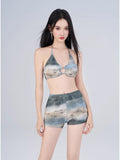 Woman modeling a halter bikini top with abstract print and matching high-waisted shorts.