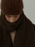 Model wearing a brown knit scarf draped over a dark brown blazer