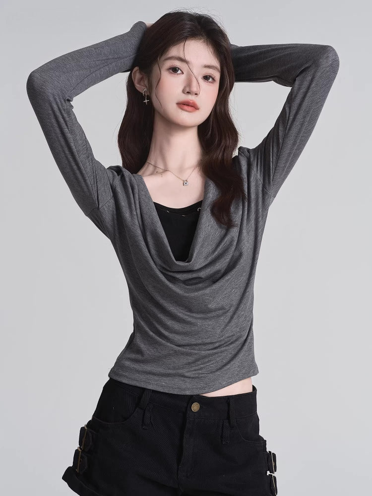 Woman in grey draped cowl neck long sleeve top and black shorts