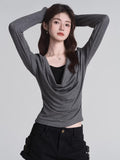 Woman in grey draped cowl neck long sleeve top and black shorts