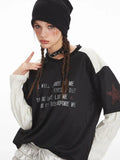 Model posing with a black and white long sleeve graphic t-shirt and silver ruffled shorts.