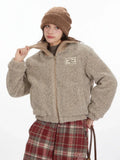 Close-up of a model adjusting the collar of a tan fleece bomber jacket.