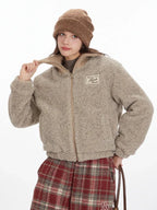 Close-up of a model adjusting the collar of a tan fleece bomber jacket.