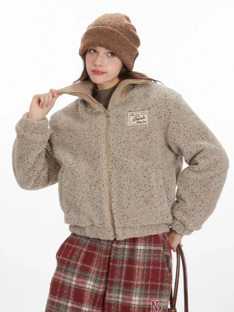 Close-up of a model adjusting the collar of a tan fleece bomber jacket.