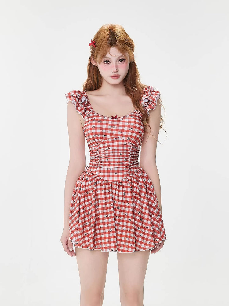Woman wearing a red and white gingham dress with ruffled sleeves and a bow accent