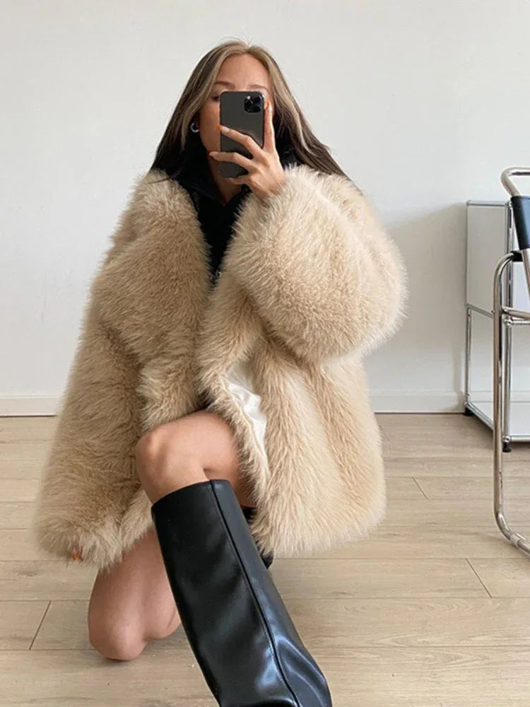 Close-up portrait of a woman with bangs wearing a cream turtleneck and a brown shaggy faux fur coat.