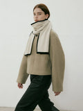 Model in a tan jacket wearing a cream and black scarf