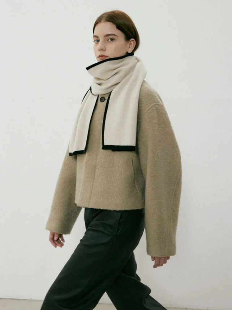 Model in a tan jacket wearing a cream and black scarf
