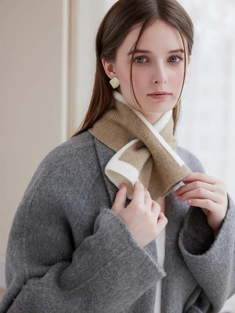 Woman wearing a grey coat and a beige and white striped knit scarf