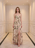 Woman wearing a cream floral print maxi dress with spaghetti straps and a high slit.